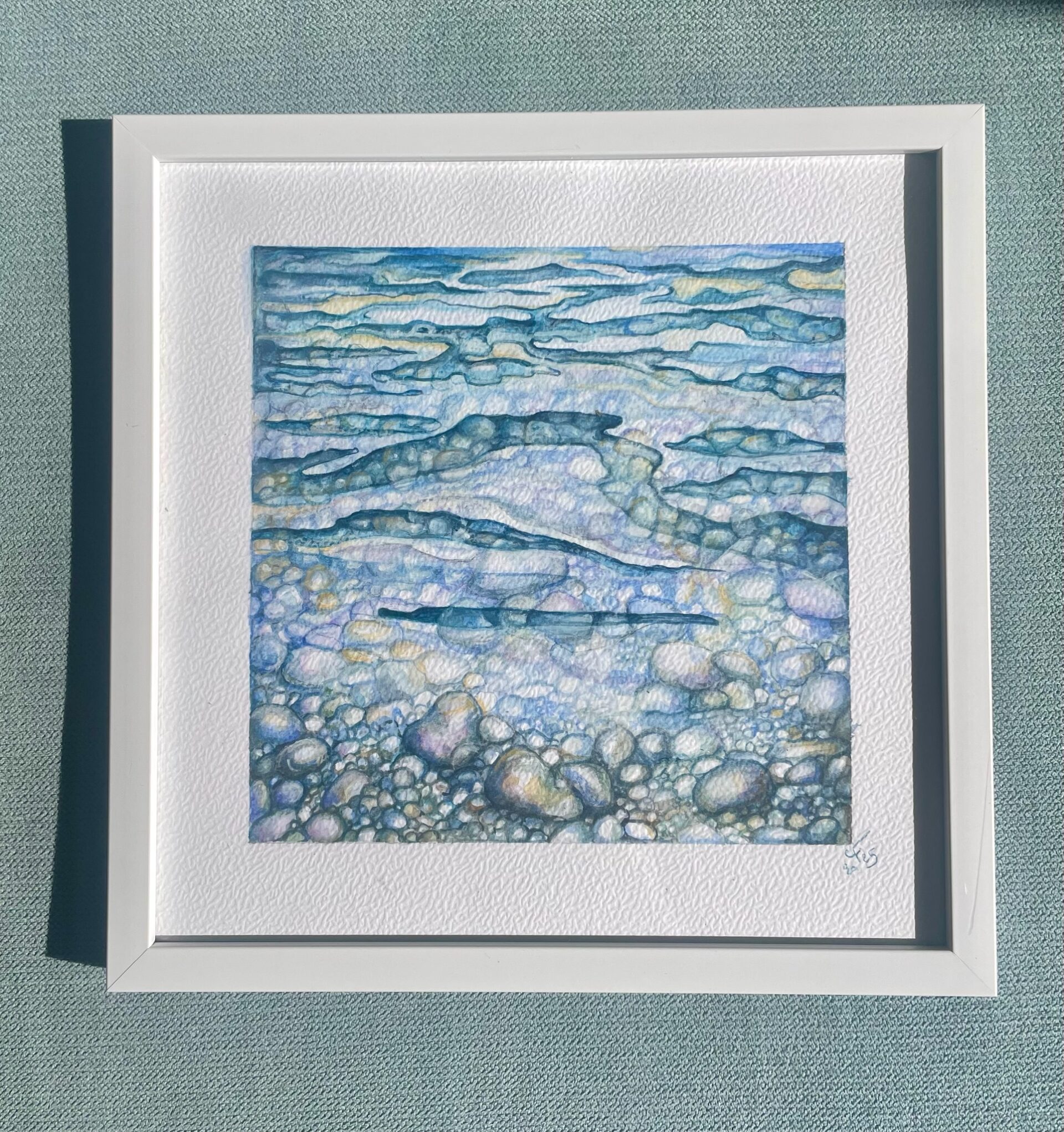 Peinture abstraite bleue évoquant des galets sous l’eau, encadrée en blanc